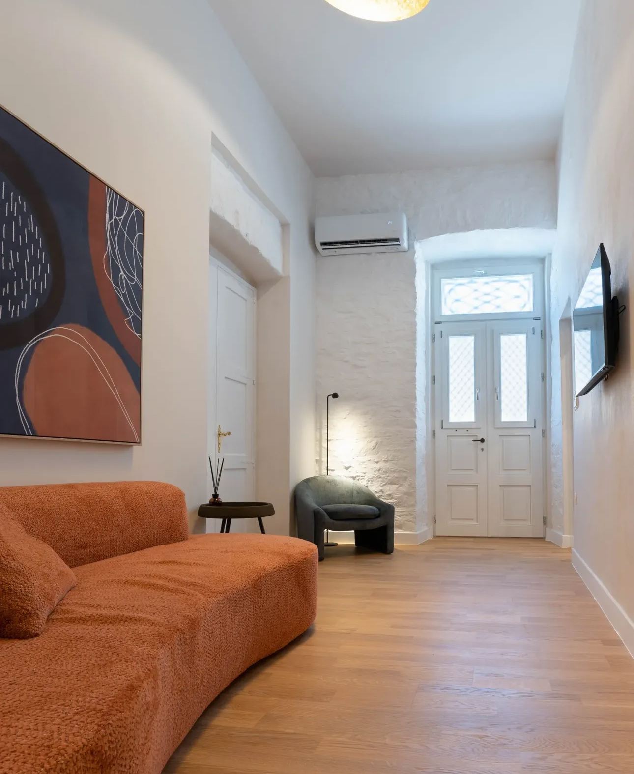 Amorosa suite lounge — terracotta bouclé sofa in a whitewashed neoclassical hallway, Syra di Giovanni 1862, Ermoupoli, Syros